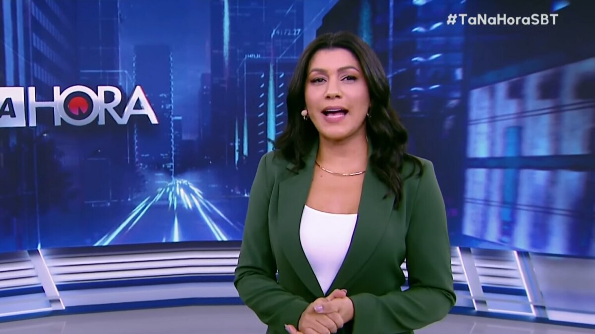 Daniele Brandi, em frente ao telão, em trecho do programa Tá na Hora
