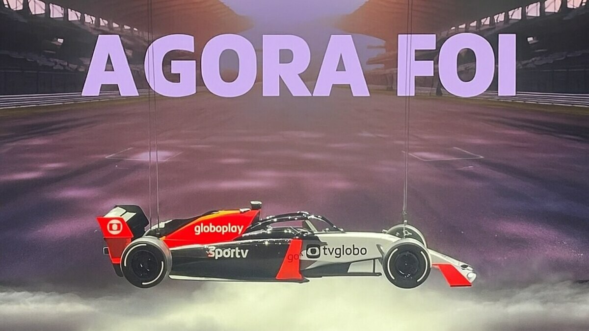 Carro de Fórmula 1 suspenso com logos da TV Globo, Globoplay e Sportv. No telão está escrito AGORA FOI