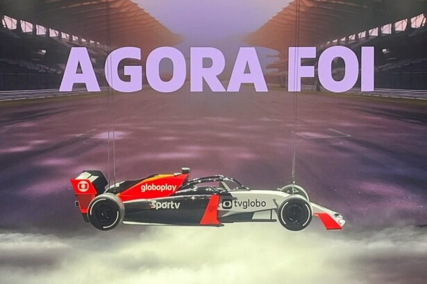 Carro de Fórmula 1 suspenso com logos da TV Globo, Globoplay e Sportv. No telão está escrito AGORA FOI