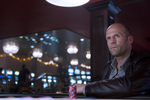 Jason Statham sentado em uma mesa de cassino em cena do filme Cartas Selvagem