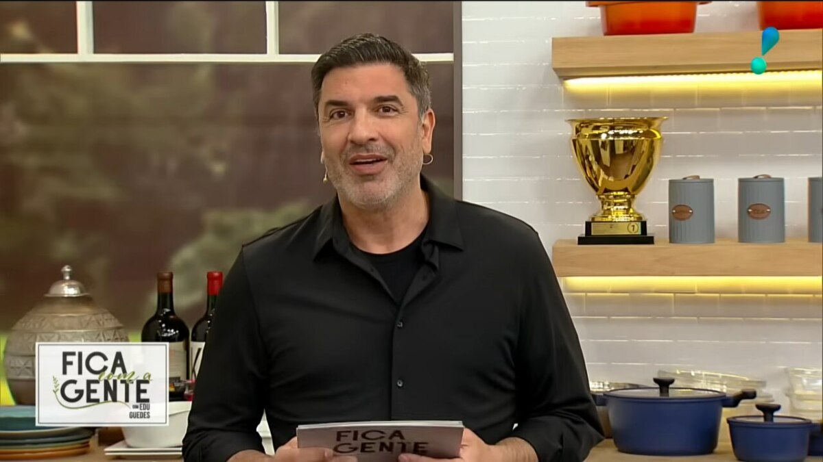 Edu Guedes veste camisa preta e sorrir, apresentando o Fica com a Gente, na cozinha da RedeTV!