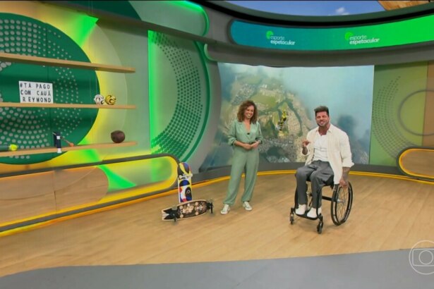Karine Alves em pé e Fernando Fernandes sentado em sua cadeira de rodas no cenário do Esporte Spectacular