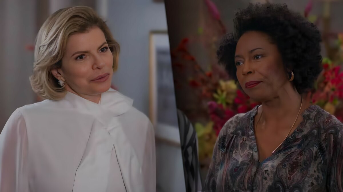 Odete olha com deboche para Eunice na casa de Celina. Ela vesta blusa branca enquanto Eunice veste uma blusa estampada preto e branco e usa um batom vermelho escuro em cena de Vale Tudo