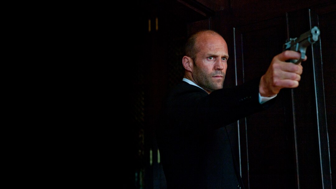 Jason Statham aponta uma arma na gravação do filme Parker