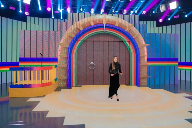 Patricia Abravanel no centro do palco na frente do cenário da Porta da Esperança no Programa Silvio Santos