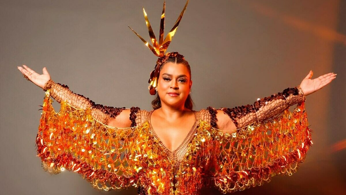 Preta Gil de roupa dourada brilhante e com os braços abertos