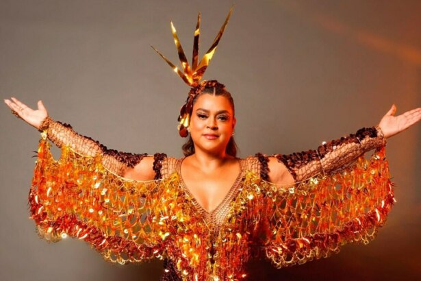 Preta Gil de roupa dourada brilhante e com os braços abertos
