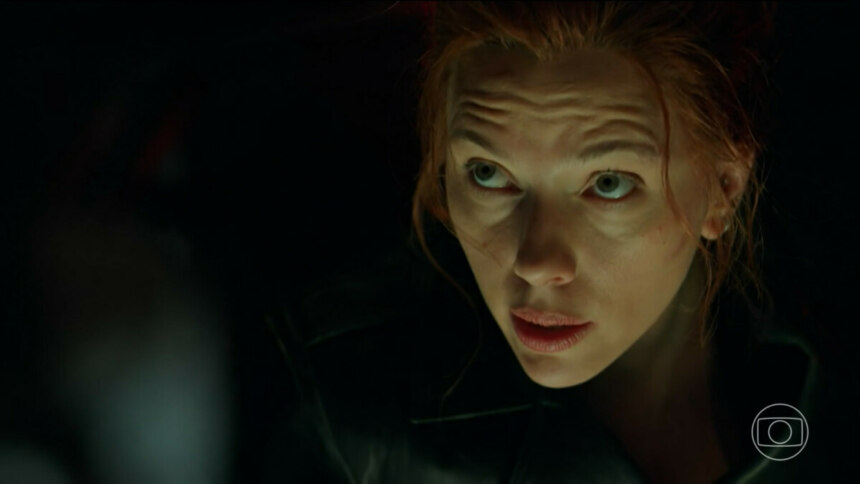 Scarlett Johansson caracterizada com roupas pretas da Viúva Negra. Ela olha assustada para cima