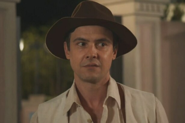 O ator Sérgio Guizé como o personagem Candinho, da novela 'Êta Mundo Melhor!', usa um chapéu de feltro marrom e uma camisa clara, com uma expressão de surpresa ou espanto.