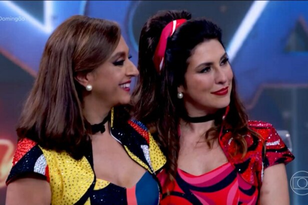 As apresentadoras Cátia Fonseca e Fernanda Paes Leme posam sorrindo. Elas usam fantasias coloridas e com lantejoulas no palco do quadro Dança dos Famosos.