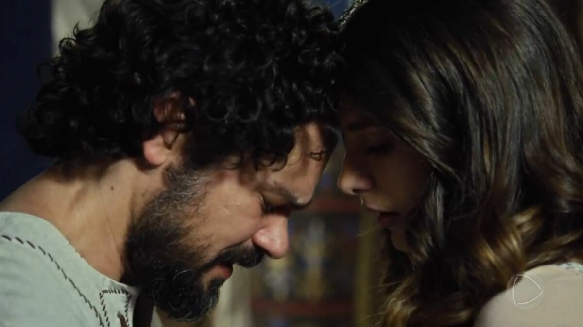 Um close-up dos atores Gabriel Gracindo e Tammy Di Calafiori, que interpretam os personagens Daniel e Lia, com os rostos próximos e encostados um no outro. O homem, de cabelo escuro e encaracolado, inclina a cabeça para a mulher, que tem o cabelo solto e castanho. O logo da Record está visível no canto inferior direito.