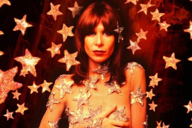 A cantora Rita Lee, com cabelos ruivos, usa uma maquiagem forte e um vestido transparente com estrelas brilhantes. O fundo da foto, que parece ser um poster de documentário, também é vermelho e cheio de estrelas.