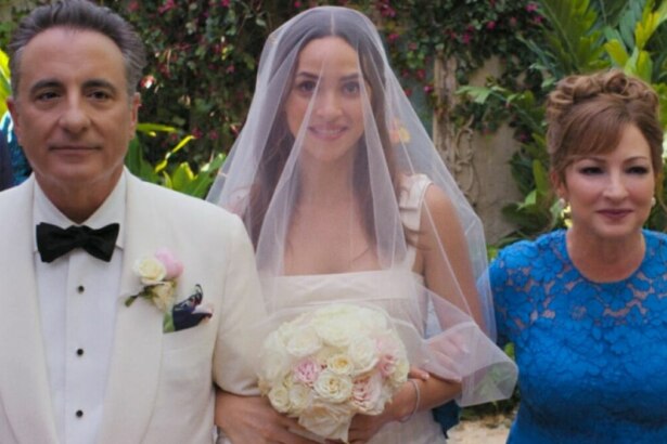 Cena do filme "O Pai da Noiva" com o pai e a mãe caminhando de braços dados com a noiva. O pai, à esquerda, usa um terno branco com gravata borboleta preta; a noiva, ao centro, usa um vestido branco, véu e segura um buquê de flores; e a mãe, à direita, usa um vestido azul de renda.