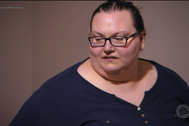 Lindsey de blusa azul, extremamente obesa, com 294 quilos, olhando para o lado e de óculos de grau
