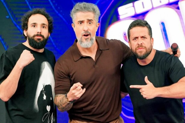 Os humoristas Maurício Meirelles e Murilo Couto, e o apresentador Marcos Mion, posam juntos no palco do programa Caldeirão. Mion, ao centro, tem uma expressão de surpresa.