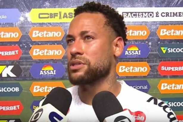 O jogador de futebol Neymar Jr., usando uma camisa branca, concede uma entrevista com expressão séria em frente a um painel de patrocinadores e fala sobre a Seleção Brasileira