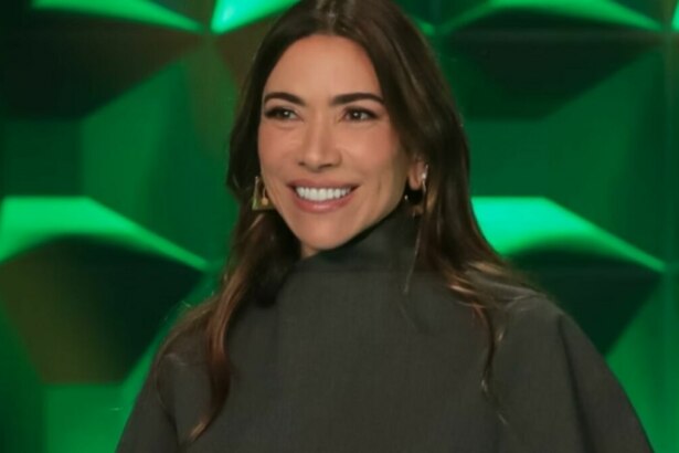 A apresentadora Patricia Abravanel, em um close-up, sorri levemente e olha para a frente. Ela usa uma blusa preta de gola alta e brincos grandes e dourados. O fundo é um cenário de estúdio com painéis verdes e triangulares. O nome do arquivo a associa ao 'Show do Milhão Celebridades'.