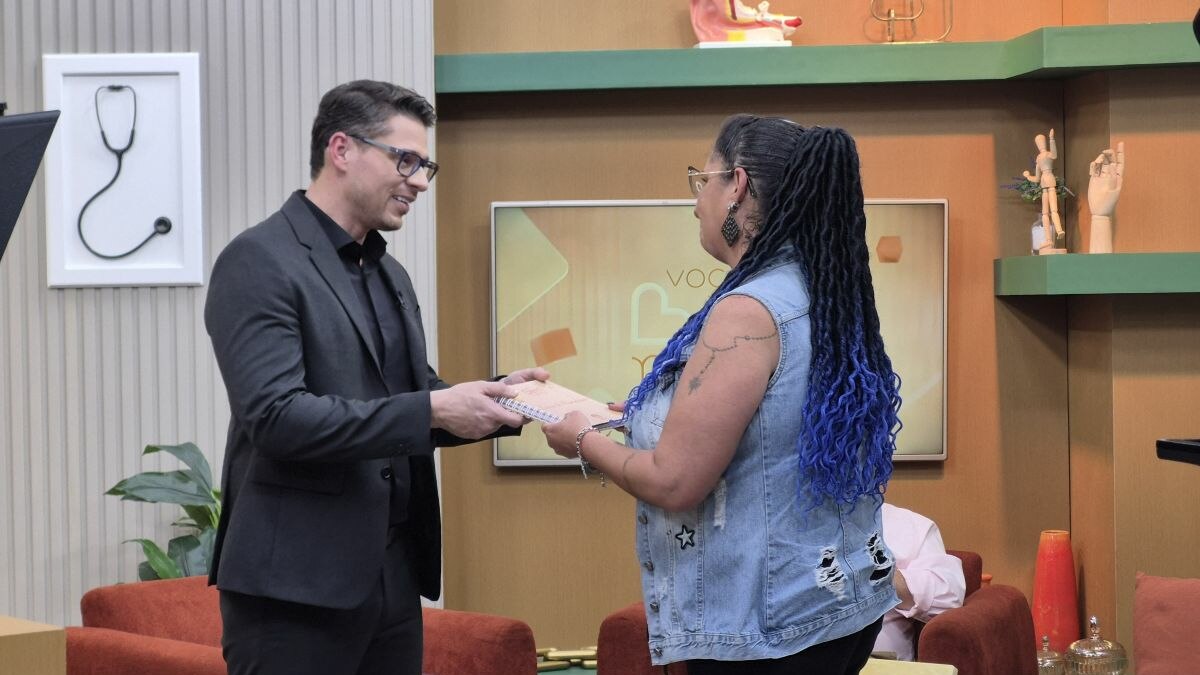 Dr. Rodrigo Gurgel segura nas mãos de Cláudia Bueno no cenário do Você Bem Melhor da TV Aparecida