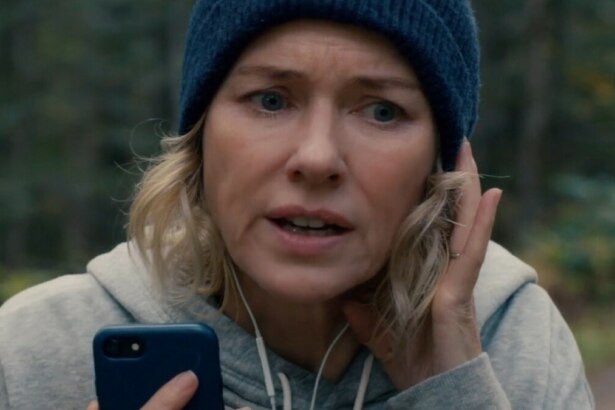 Protagonista do filme A Hora do Desespero com gorro azul e fone ajustando o áudio enquanto caminha, em clima de suspense e concentração.