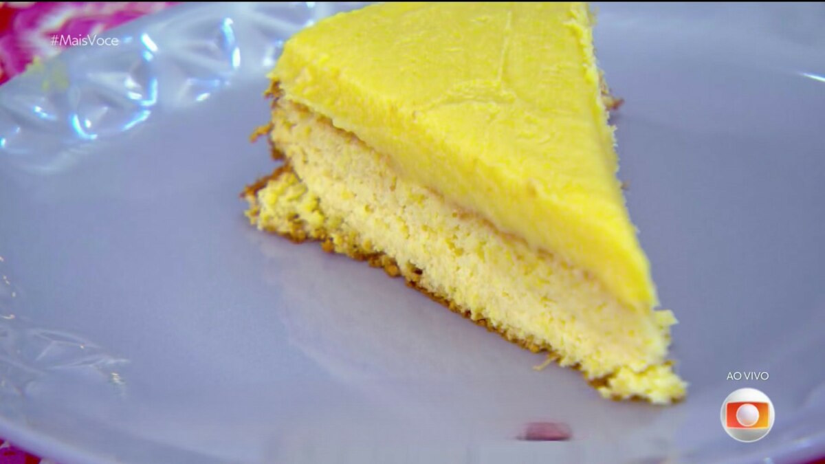 Fatia de bolo curau cremoso com cobertura brilhante, servida em prato lilás no Mais Você, receita de Ana Maria Braga.