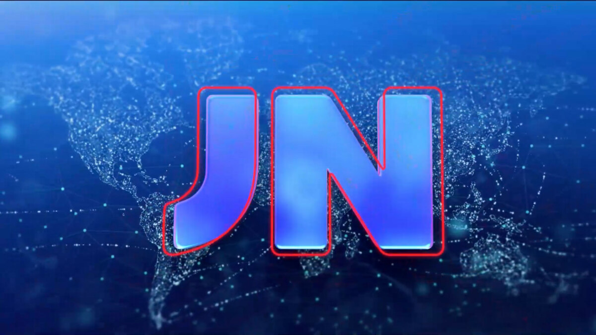 Logotipo atualizado do Jornal Nacional, com as letras ‘JN’ em azul e contorno vermelho sobre um fundo escuro que exibe um mapa-múndi estilizado em pontos e linhas luminosas
