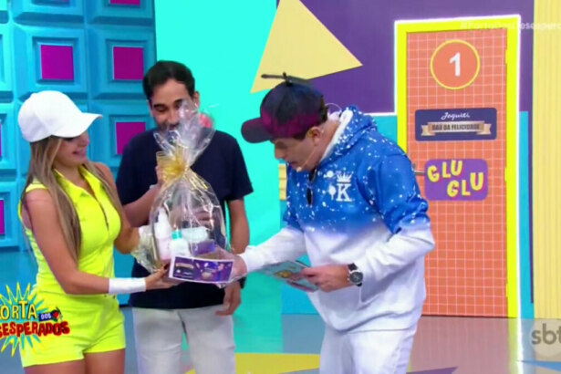 Sergio Mallandro observa carnê do Baú na cesta de presentes de um fã do SBT no palco do Porta dos Desesperados