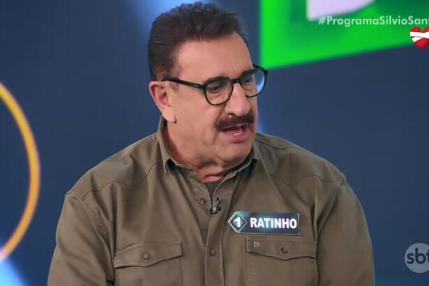 Apresentador Ratinho no palco do Programa Silvio Santos, usando camisa marrom com plaqueta de nome, durante participação no Show do Milhão Celebridades, onde declarou estar invicto na vice-liderança há 27 anos no SBT