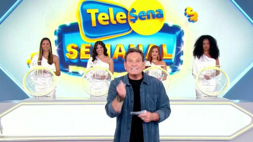 O apresentador Luis Ricardo no palco, com quatro modelos ao fundo, em um cenário de sorteio da Tele Sena Semanal