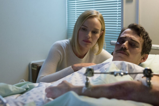 Cena do filme 90 Minutos no Paraíso, com uma mulher loira e séria observando um homem deitado em uma cama de hospital, com machucados no rosto.