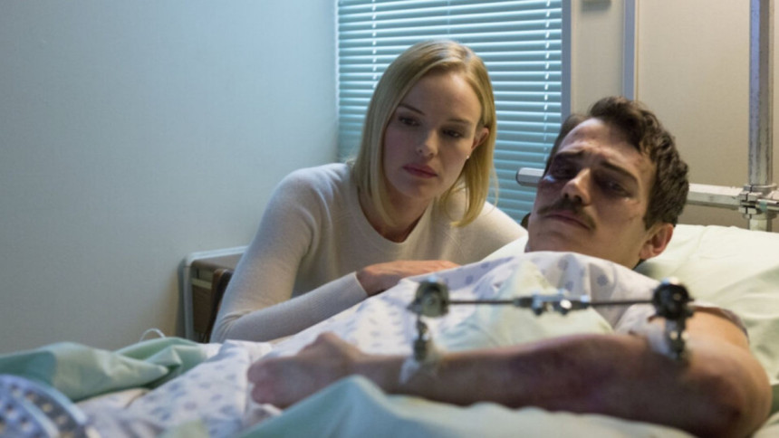 Cena do filme 90 Minutos no Paraíso, com uma mulher loira e séria observando um homem deitado em uma cama de hospital, com machucados no rosto.
