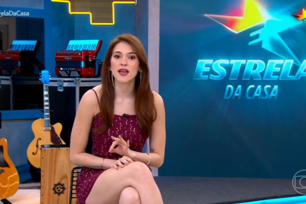 Ana Clara sentada em frente ao telão no cenário do Estrela da Casa