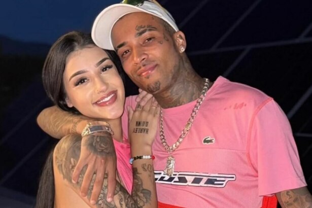Bia Miranda abraçada com o companheiro Gato Preto, sorrindo para a câmera em uma foto tirada à noite.
