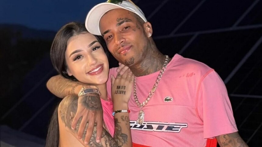 Bia Miranda abraçada com o companheiro Gato Preto, sorrindo para a câmera em uma foto tirada à noite.