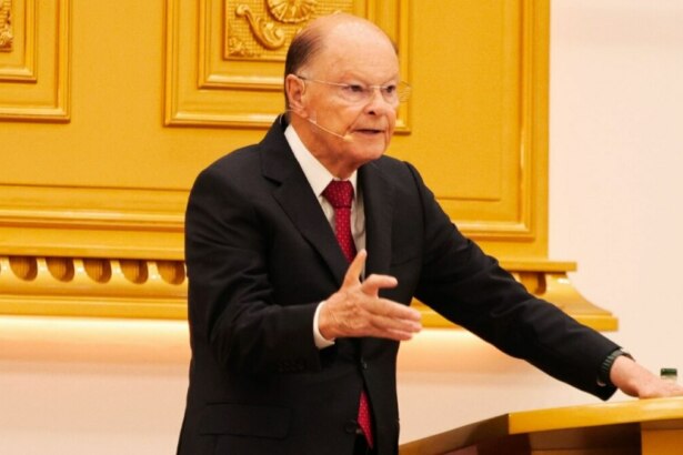 Bispo Edir Macedo, de terno preto e gravata vermelha, em pé atrás de um púlpito dourado, gesticulando com a mão direita em um culto da Igreja Universal do Reino de Deus.
