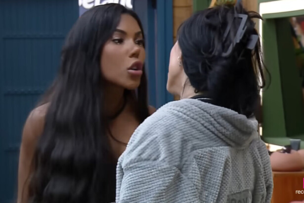 As participantes Rayane, de cabelos escuros e lisos, e Carol, de cabelos trançados, discutem de perto em uma cena do reality show A Fazenda. Rayane está falando em um tom confrontacional, enquanto Carol a encara.