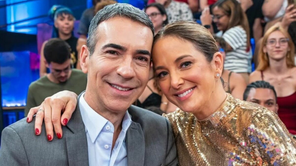 O jornalista Cesar Tralli e a apresentadora Ticiane Pinheiro sorriem juntos para uma foto em um estúdio de TV.