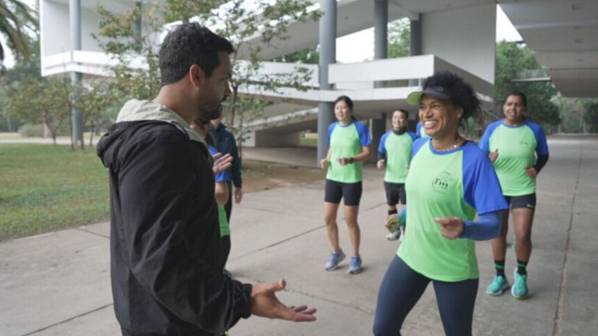 Reportagem do Globo Repórter sobre corrida: uma mulher sorri, correndo com camisa verde e azul, enquanto um homem a entrevista em um parque.