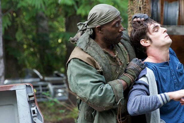 Cena do filme Invasão Alienígena com o ator Wesley Snipes segurando outro homem pelo pescoço em uma floresta, com a caçamba de uma picape ao lado.