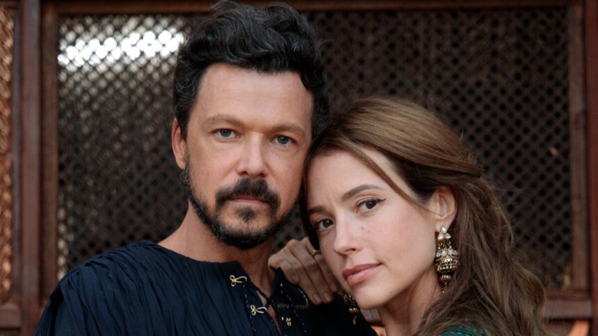 O ator Guilherme Berenguer, com barba e cabelos escuros, e a atriz Juliana Didone, com cabelo castanho claro e longos brincos dourados, posam juntos. A mão de Juliana está no ombro de Guilherme, em uma foto promocional da minissérie A Vida de Jó.