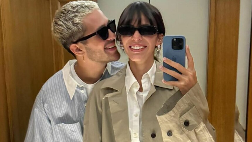 Bruna Marquezine e João Guilherme posando para uma selfie. Bruna está segurando o celular e sorrindo, enquanto João a abraça por trás e sorri, ambos usando óculos escuros.