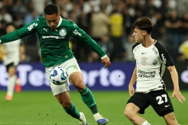 Jogador do Palmeiras, de camisa verde, chuta a bola enquanto jogador do Corinthians, de camisa branca, corre em sua direção, em partida do Brasileirão.