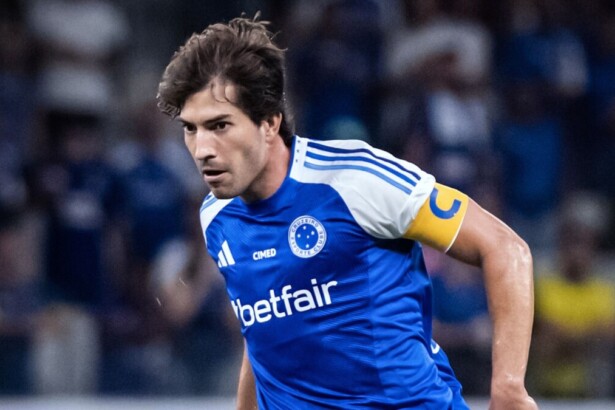 O jogador de futebol Lucas Silva, do Cruzeiro, veste uma camisa azul com detalhes brancos e a faixa de capitão amarela celebrando gol