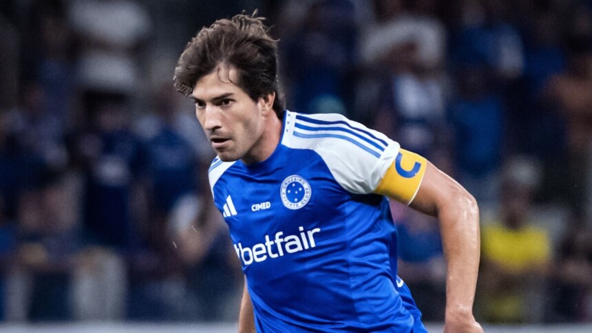 O jogador de futebol Lucas Silva, do Cruzeiro, veste uma camisa azul com detalhes brancos e a faixa de capitão amarela celebrando gol