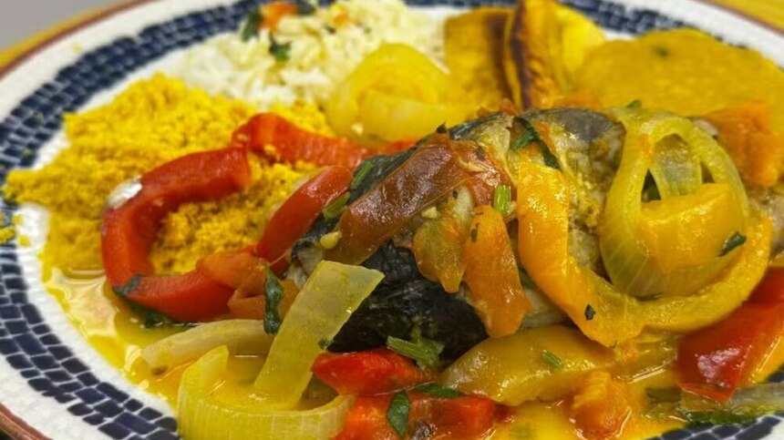 Moqueca de anchova da Talitha Morete bem temperada em cima de um prato branco no balcão do É De Casa
