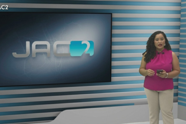 Quésia Melo em frente ao televisor no cenário do Jornal do Acre