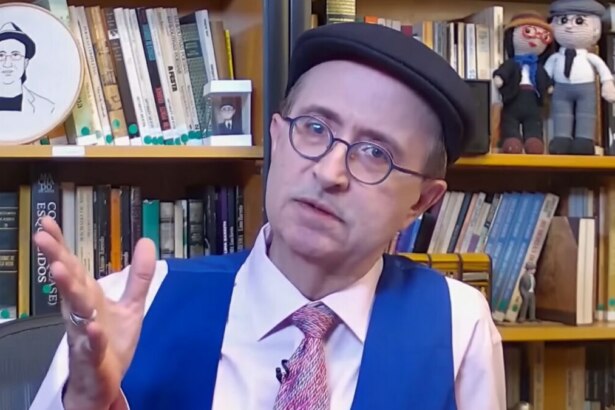 Reinaldo Azevedo apresenta “O É da Coisa” na BandNews FM, em cenário com livros e bonecos personalizados.