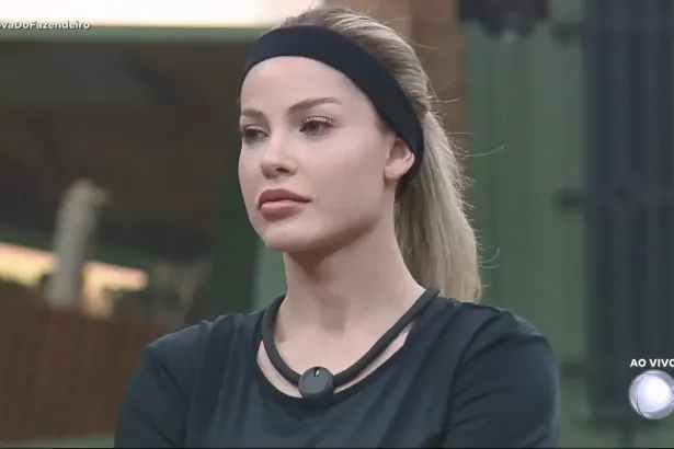 Saory Cardoso com faixa preta na cabeça em pé na sala de A Fazenda 17
