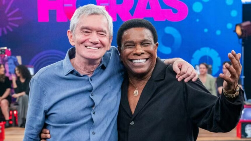 O apresentador Serginho Groisman e o cantor Luiz Carlos, do Raça Negra, abraçados e sorrindo no palco do programa Altas Horas.