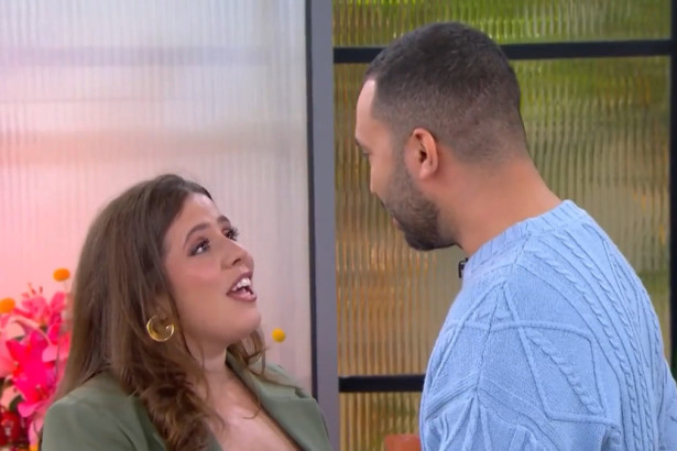 Tati Machado e Gil do Vigor se olham sorrindo e com carinho no cenário do programa Mais Você. Ela usa um blazer verde e ele, um suéter azul.