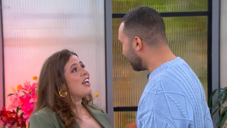Tati Machado e Gil do Vigor se olham sorrindo e com carinho no cenário do programa Mais Você. Ela usa um blazer verde e ele, um suéter azul.